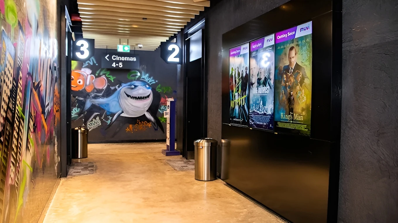 Muvi Cinemas Jubail Mall hallway with movie posters and graffiti art.