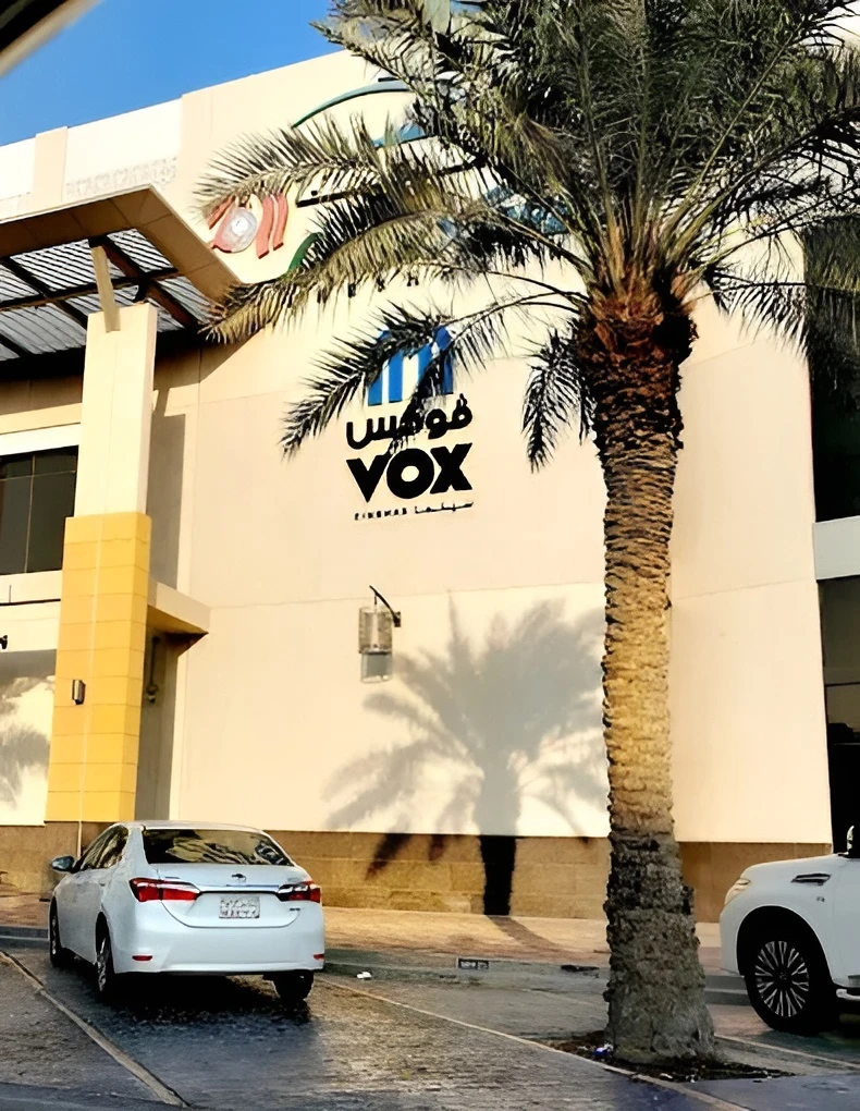 VOX Cinemas Jubail entrance with palm tree and parked cars.