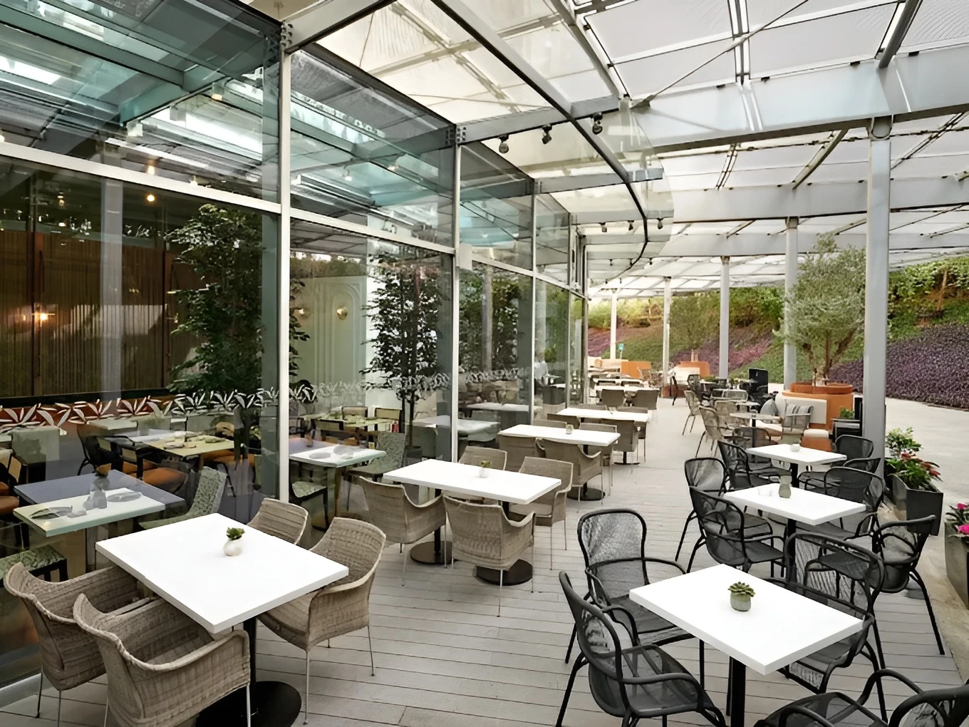 Glass-roofed patio with wicker chairs at Twisted Olive, Doha.