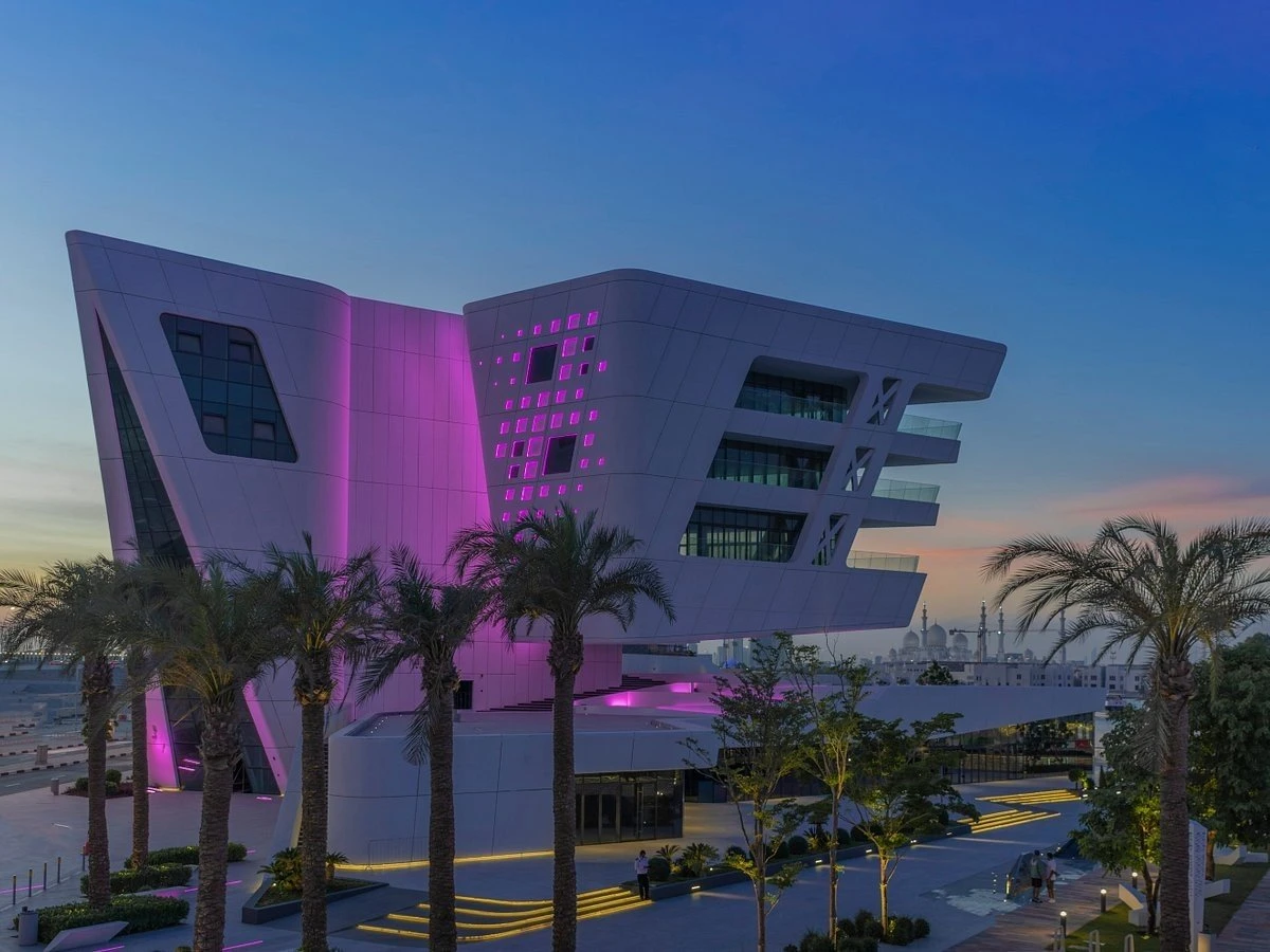 Al Qana venue in Abu Dhabi illuminated with purple lights at dusk.