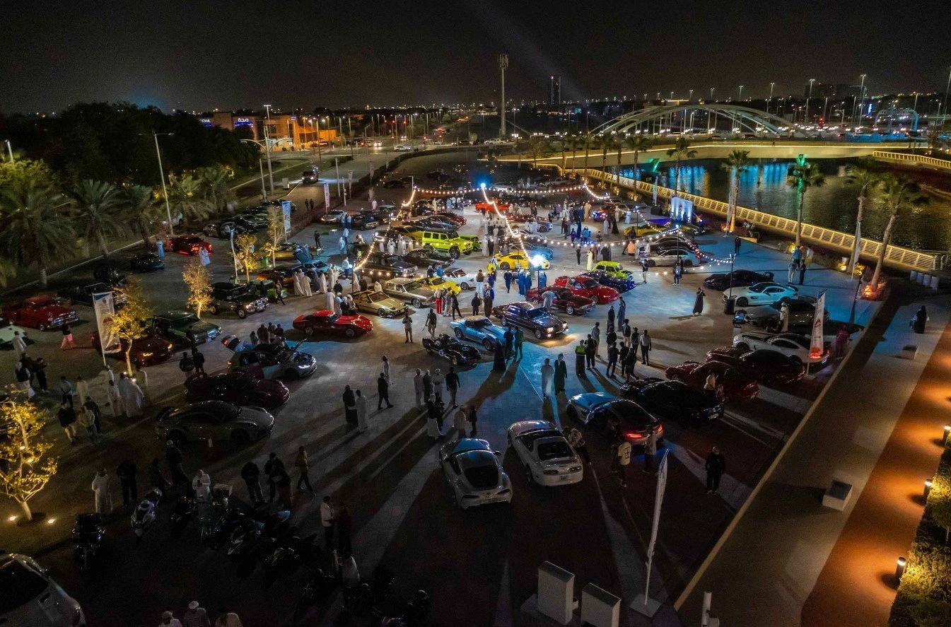 Nighttime car event at Al Qana, Abu Dhabi, with attendees.