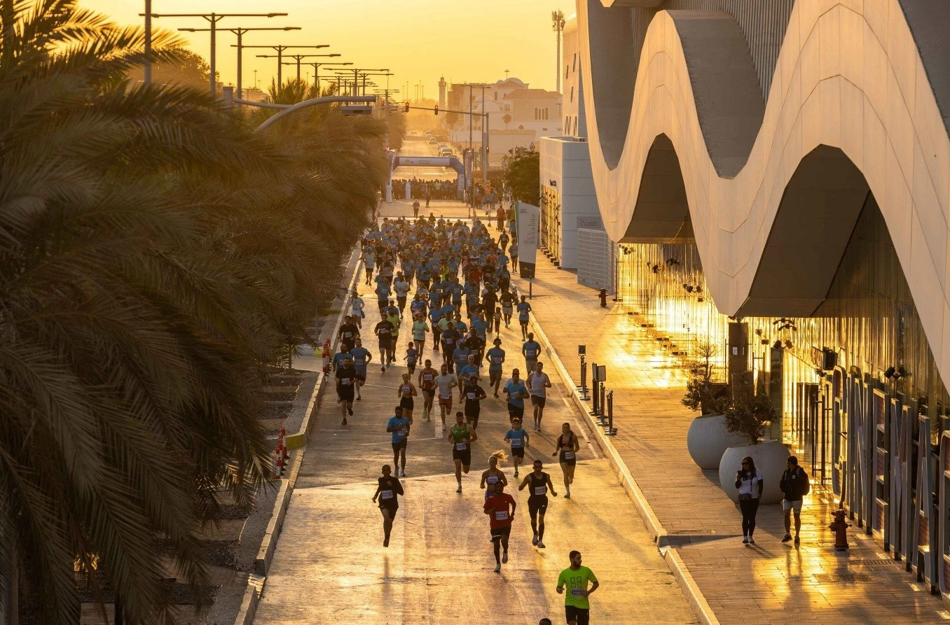 Runners at sunrise, Al Qana, Abu Dhabi, modern architecture on right.