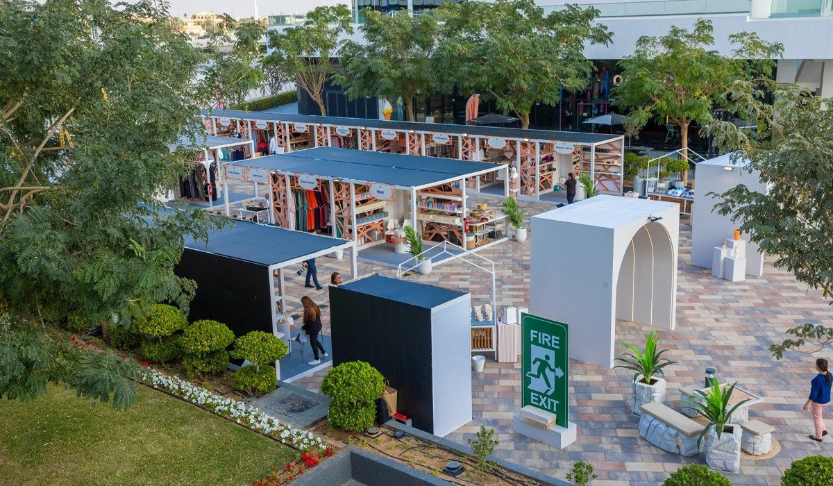 Outdoor market stalls at Al Qana, Abu Dhabi, surrounded by trees.