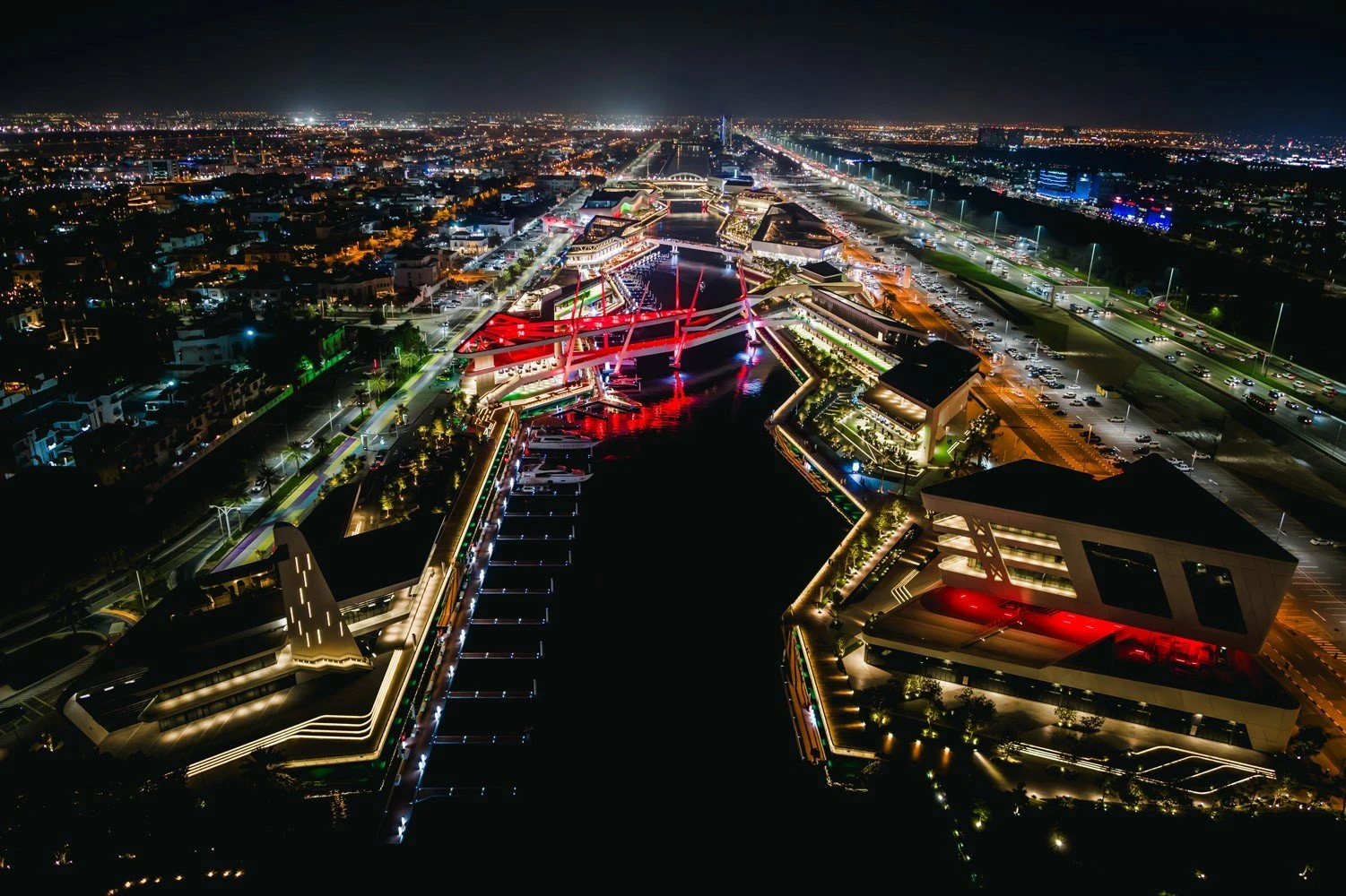 Al Qana Abu Dhabi illuminated at night with vibrant city lights.
