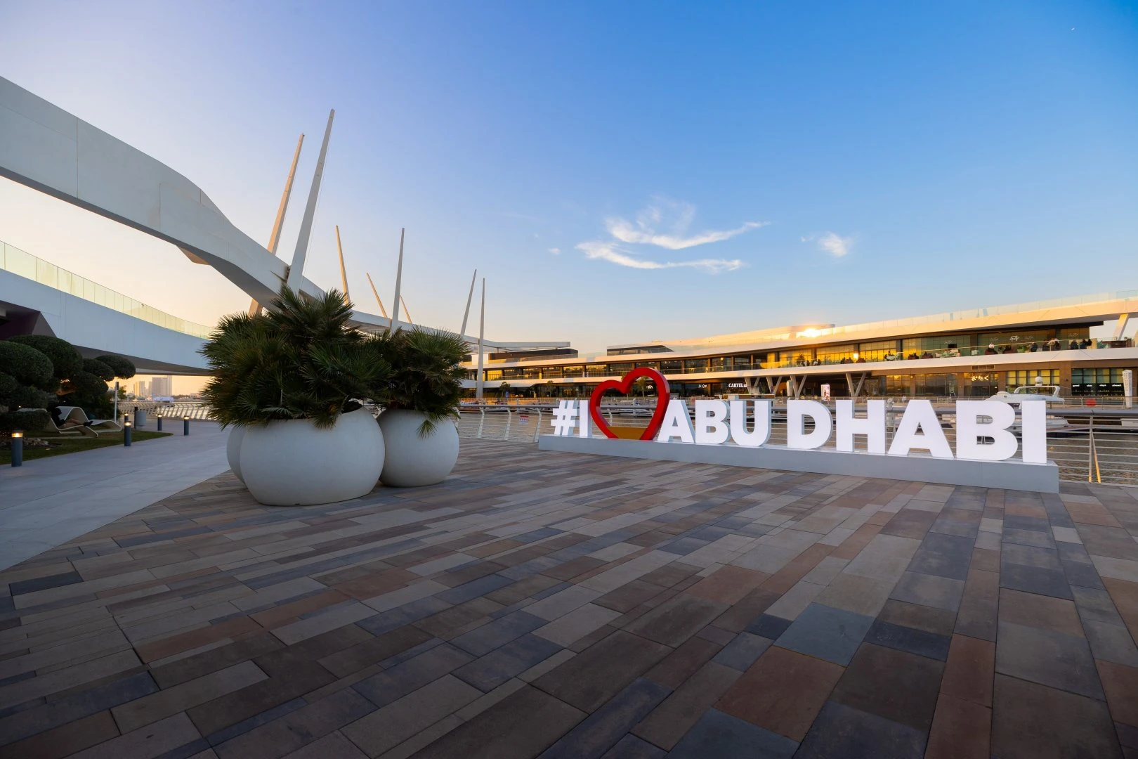 Al Qana promenade with I Love Abu Dhabi sign at sunset.