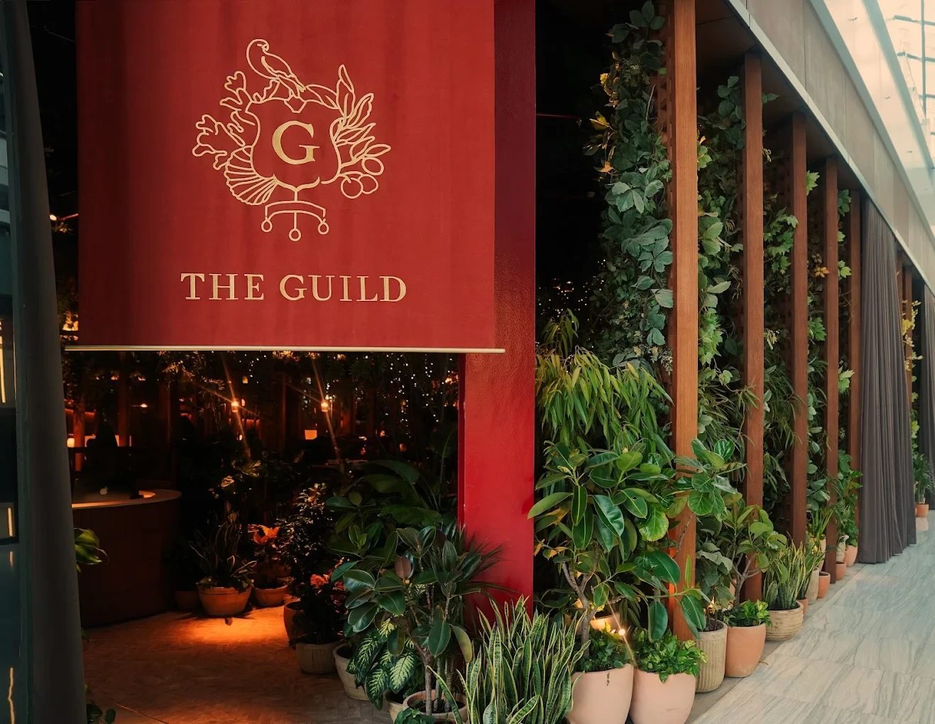 The Guild Dubai entrance with lush greenery and red sign.