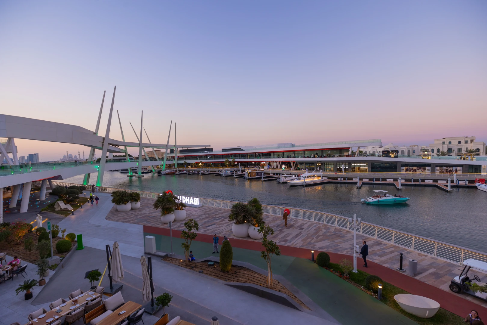 Al Qana waterfront at sunset, Abu Dhabi, with boats and walkways.