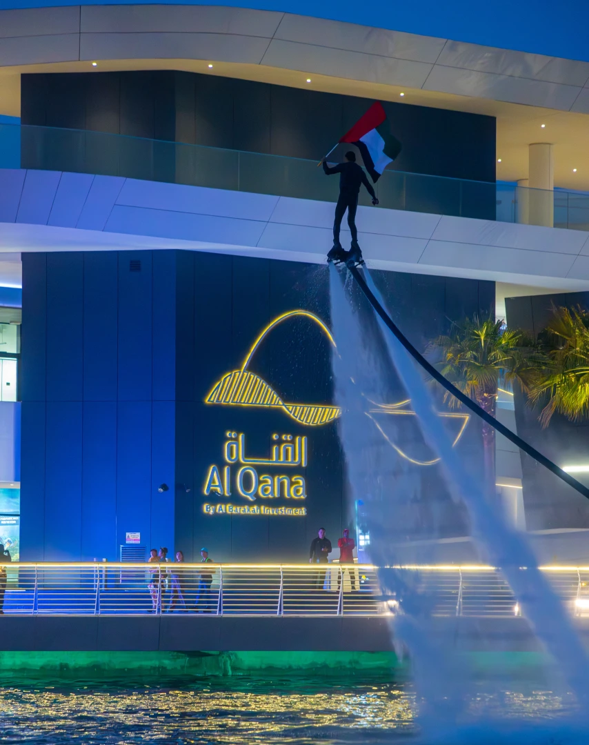 Flyboarder with UAE flag at Al Qana, Abu Dhabi waterfront.