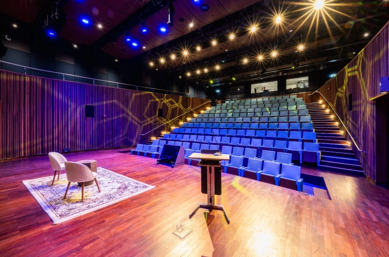 Expo City Dubai auditorium with stage and seating, vibrant lighting.