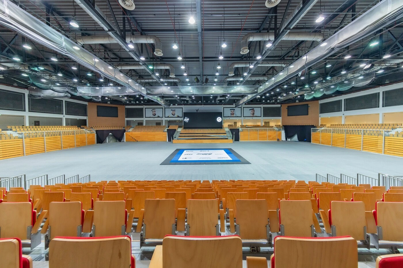 Interior of Mubadala Arena, Abu Dhabi, with empty seating and stage.