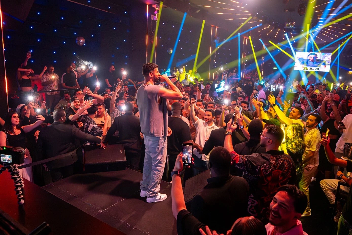 Crowded concert at OX Club Doha with vibrant lights and performer.