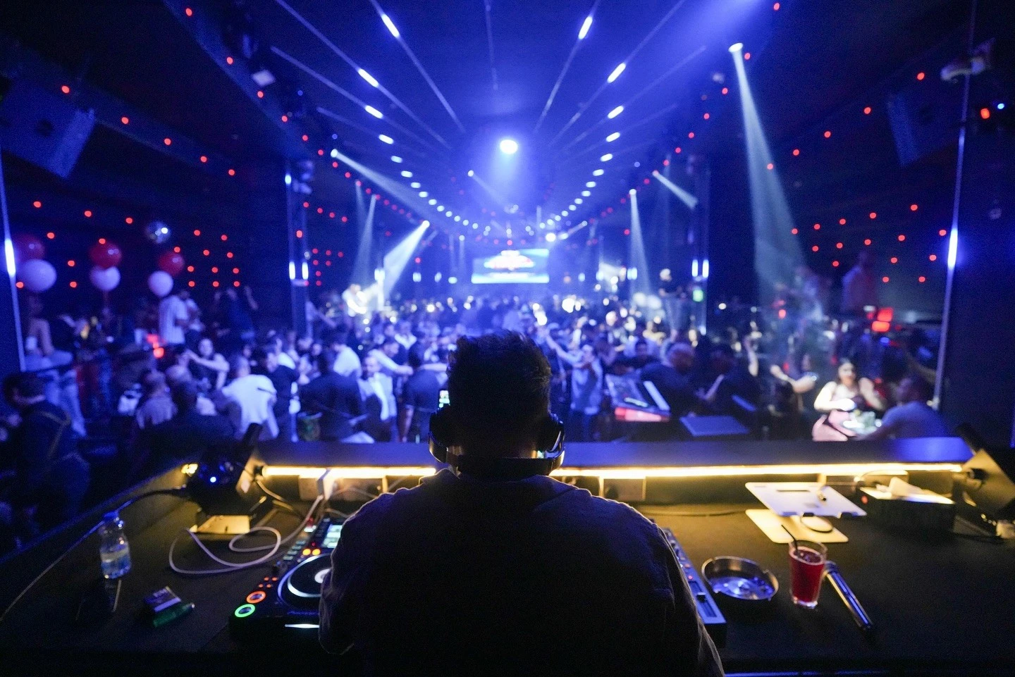 DJ performing at OX Club Doha with vibrant crowd and lights.