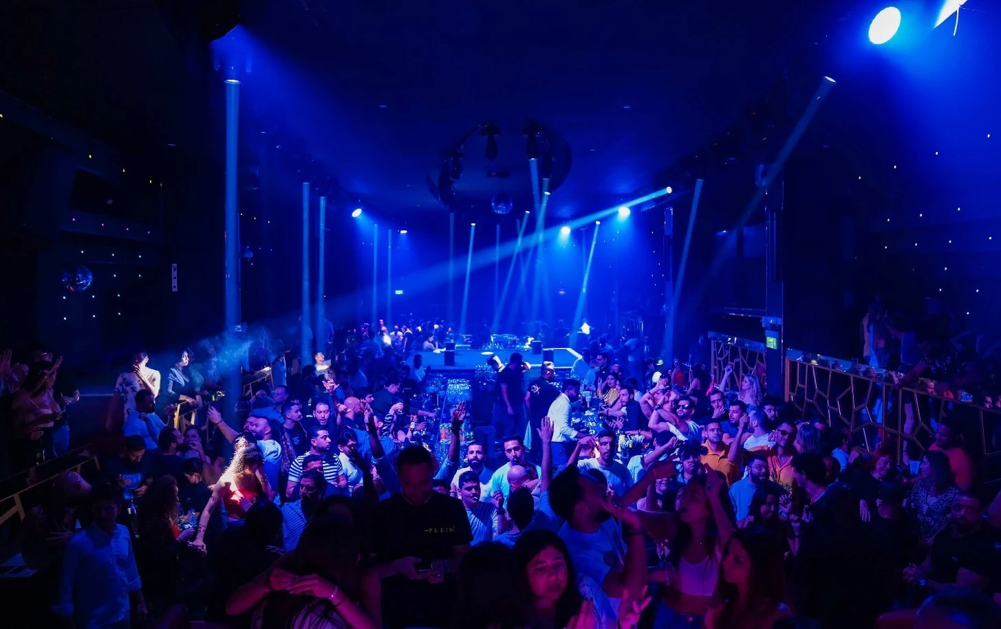 Crowded nightclub with blue lighting at OX Club Doha.