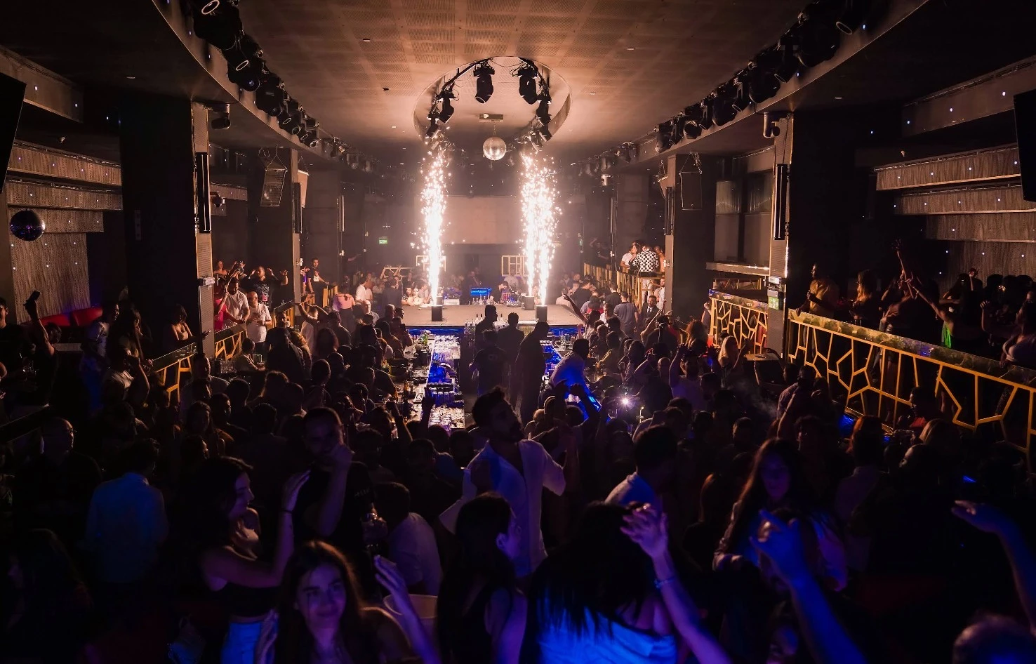 Crowded nightclub with vibrant lights at OX Club Doha.