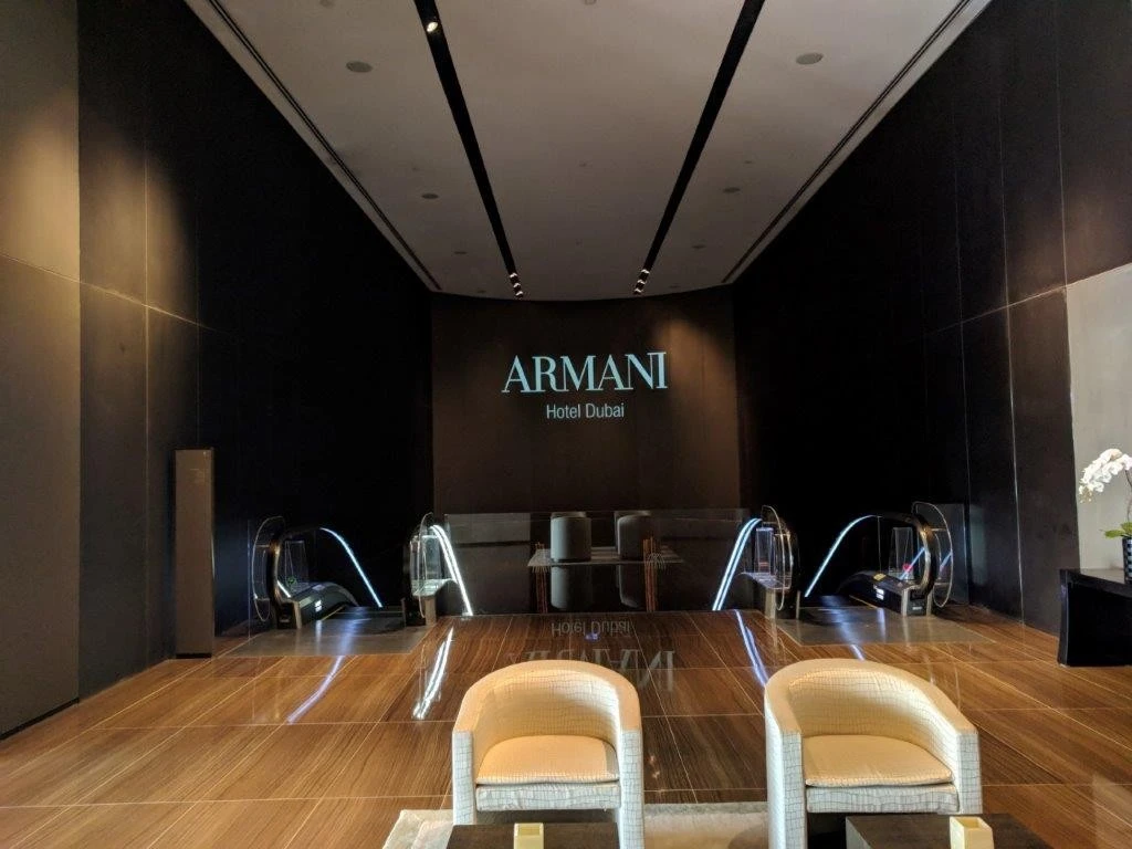 Elegant entrance of Armani Hotel Dubai with escalators and seating.
