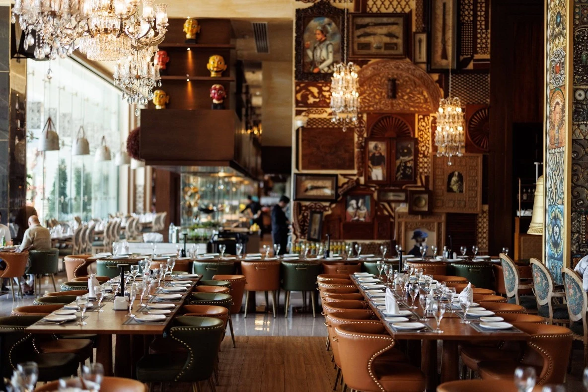 Elegant dining area at Tanatan Dubai with chandeliers and artwork.