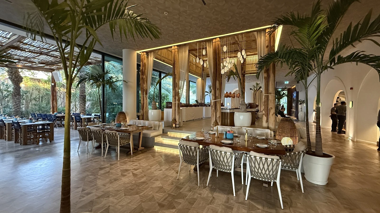 Elegant interior of Nammos Dubai with dining tables and palm decor.