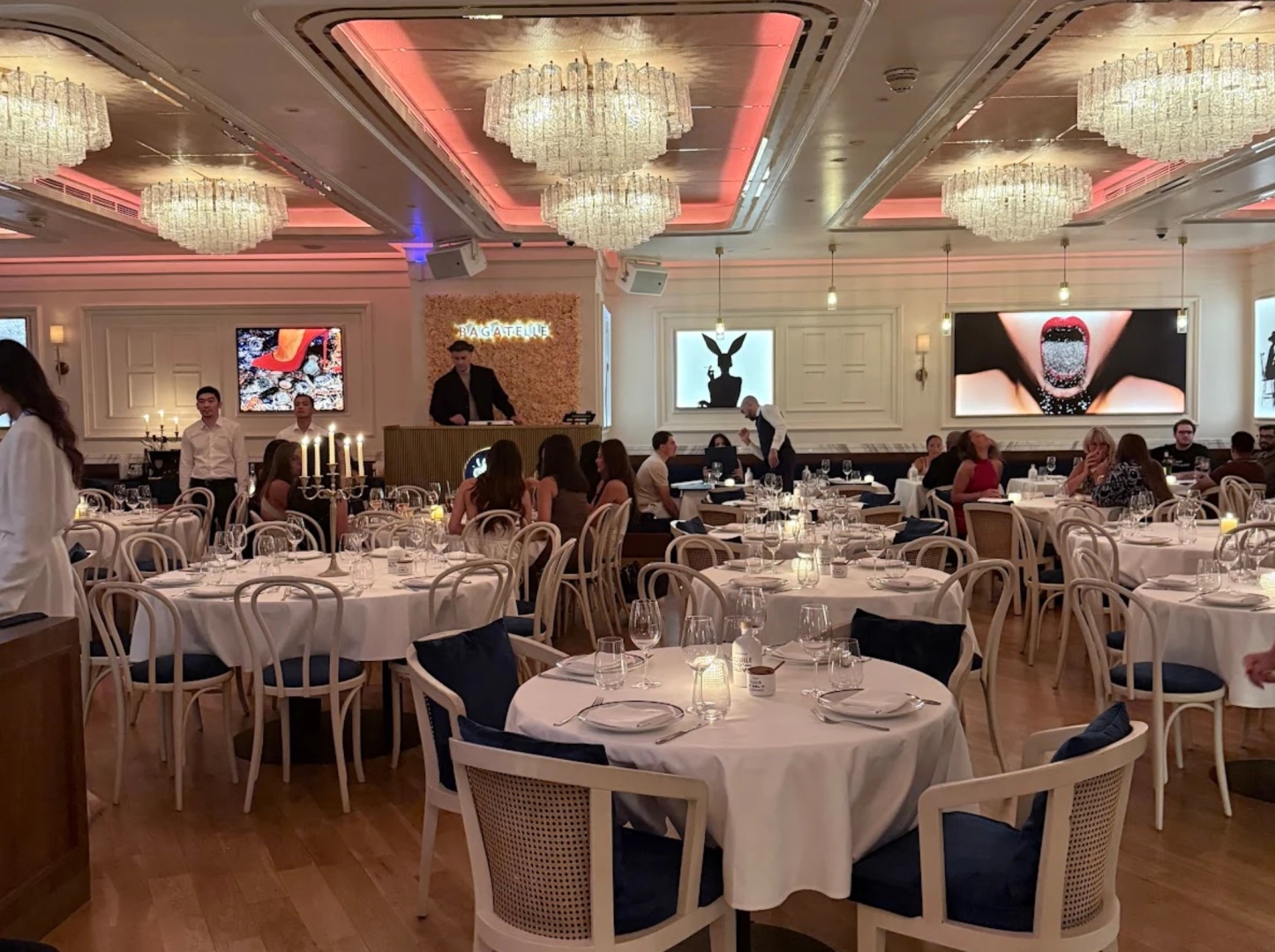 Elegant dining setup at Bagatelle Dubai with chandeliers and artwork.
