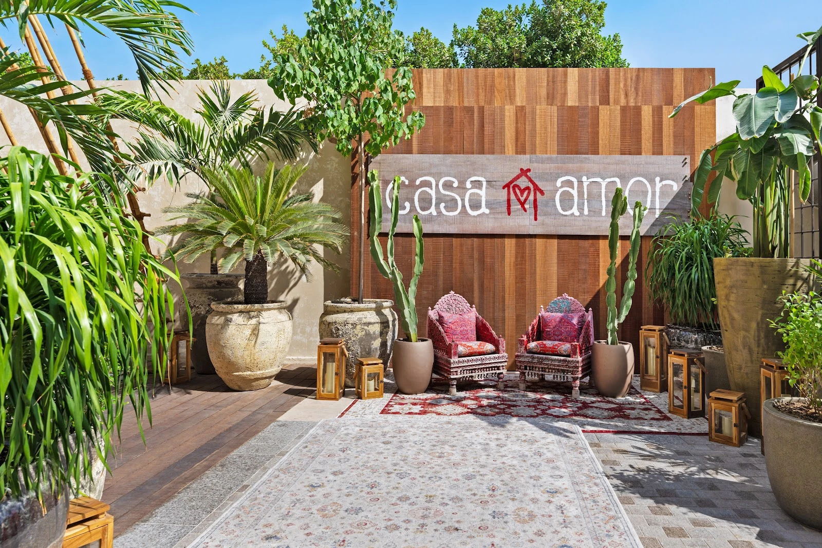 Casa Amor Dubai courtyard with lush plants and colorful seating.