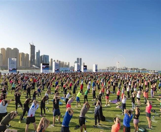 Large outdoor yoga class at Skydive Dubai, Dubai, UAE with city skyline backdrop.
