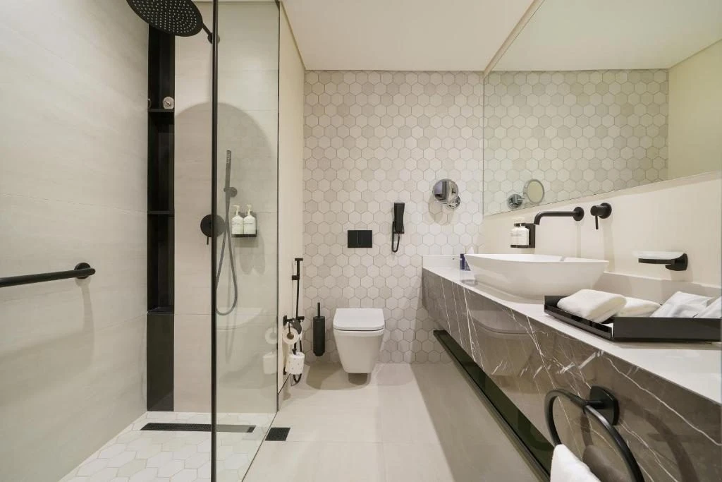 Modern bathroom with glass shower and marble sink at Nova M Hotel Riyadh Edge.