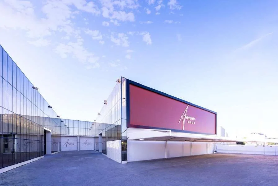 Modern exterior of Aureum Club, Dubai, UAE with large red signage.